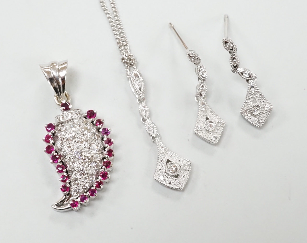 A modern white metal ruby and diamond cluster set drop pendant, modelled as a pear, overall 26mm, together with a modern 375 white metal pendant, 25mm, on a 9ct white gold chain and a pair of matching drop earrings, one